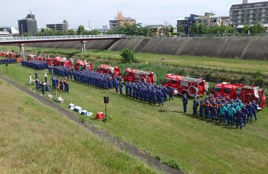 大正川河川敷にて。消防車がずらりと並び、消防団毎に整列してスタートした開始式の様子。