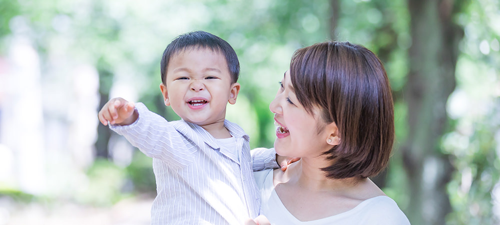 赤ちゃんを抱っこしている母親と、前を指さす赤ちゃんの写真