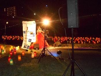 たくさんのろうそくに囲まれて赤いドレスを着た女性が歌っている