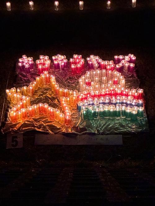 カラフルな光をまとったろうそくでキラキラキッズ文字と下に星と子供が表現されている