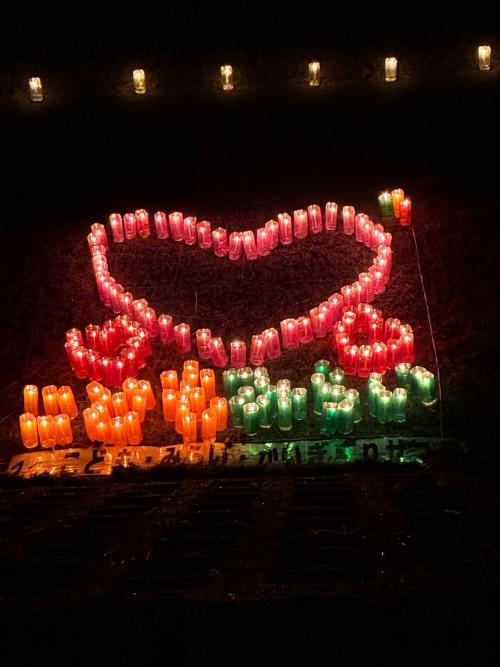 大きなピンクのハート1つと小さなハート2つ。その下にオレンジの光で「こども」その隣に緑の光で「みらい」