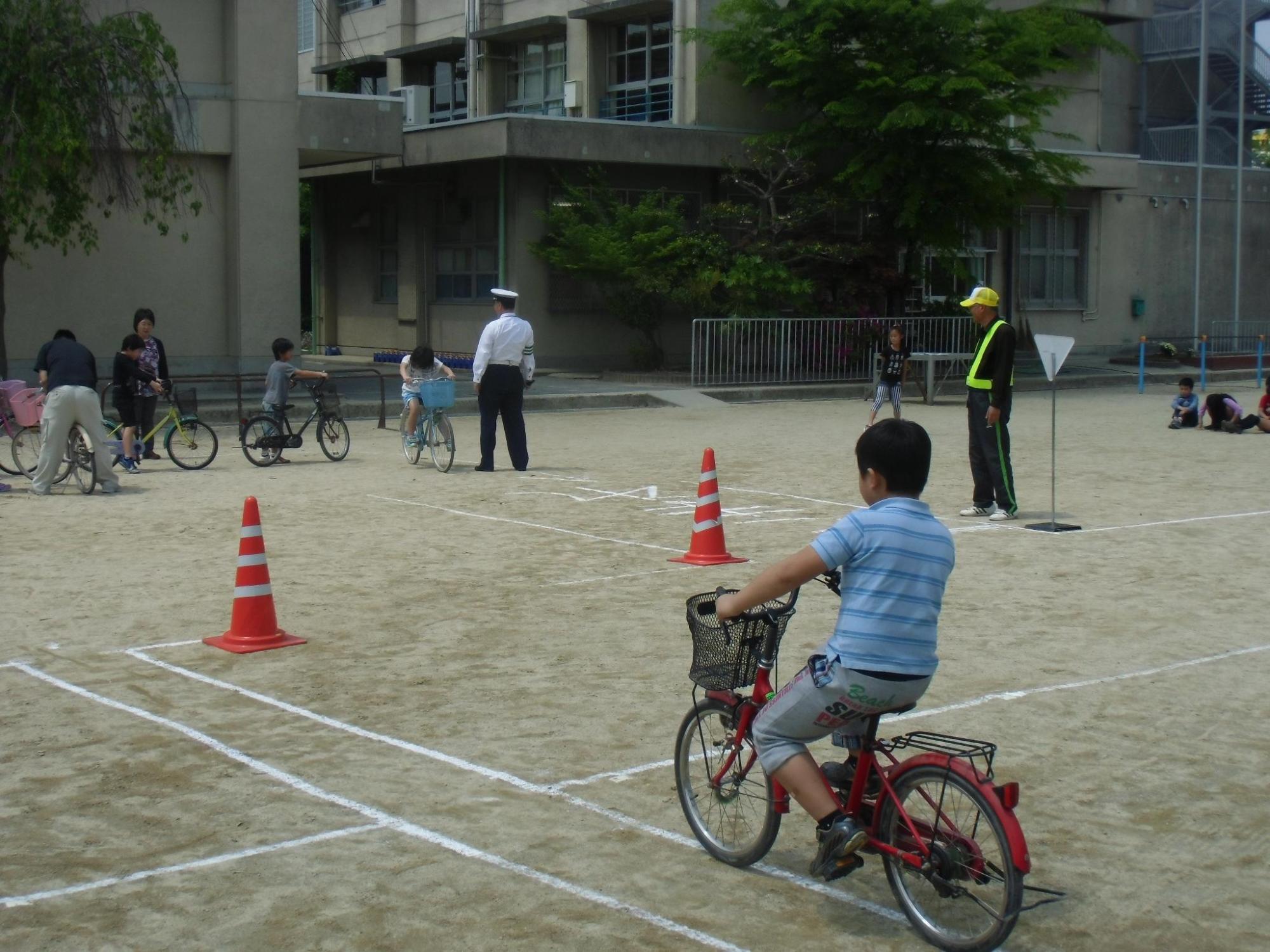 校庭に設置した模擬コースを自転車に乗って走行体験している写真